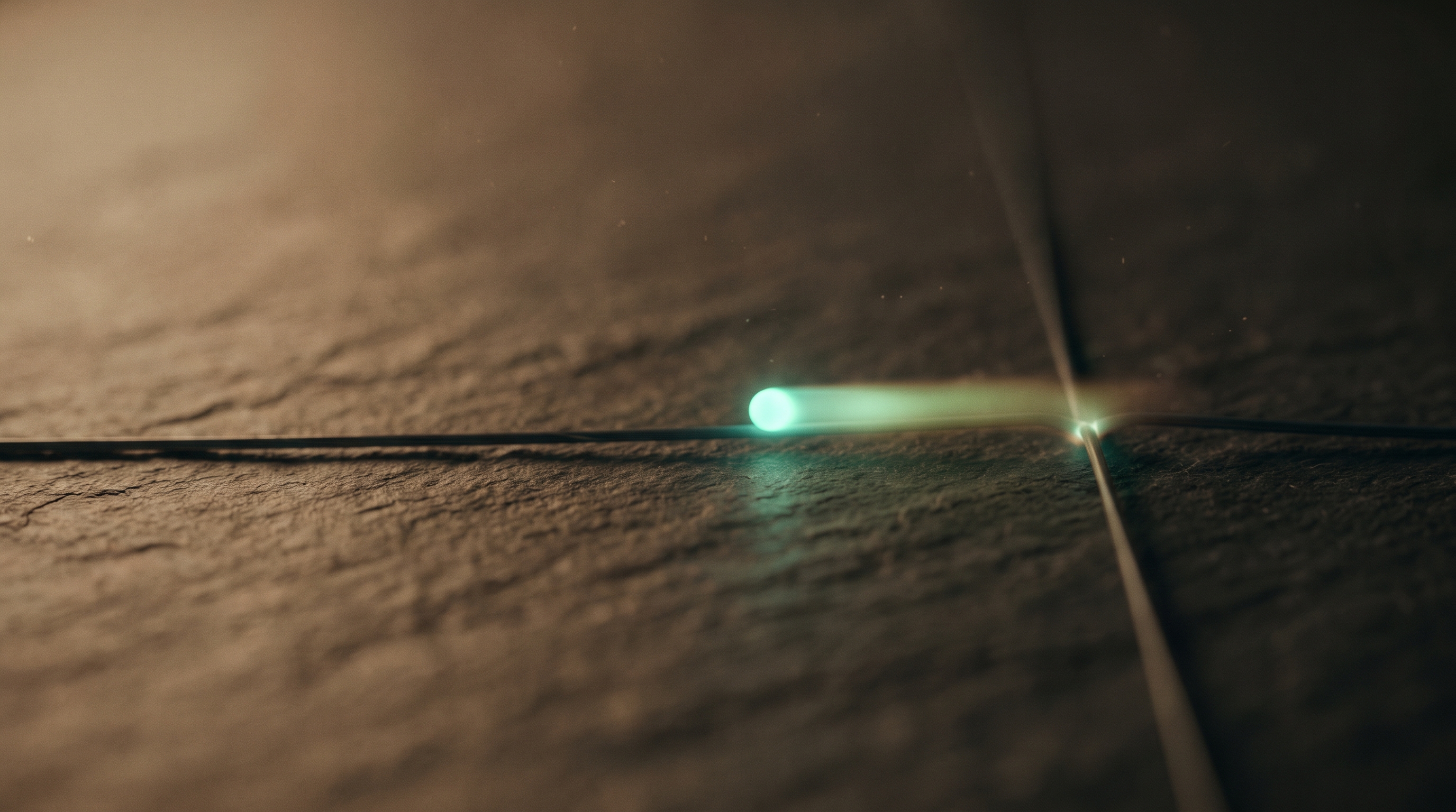 A single mint-teal light pulse traveling along a thin line across warm dark slate